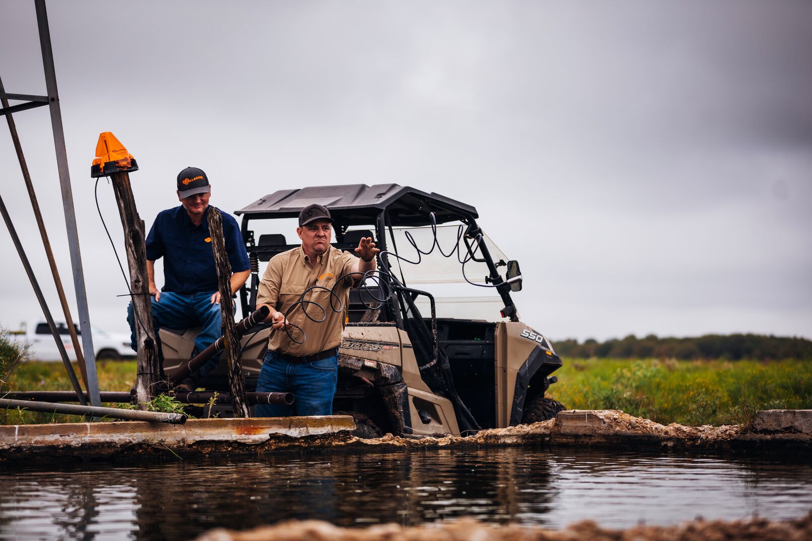 Two men standing in a ute setting up farming equipment