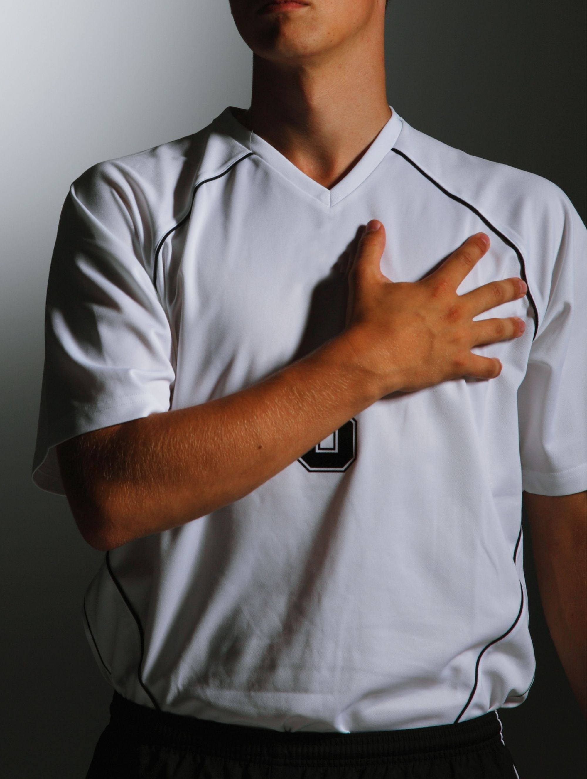 Un hombre de pie con el brazo izquierdo cruzado sobre el pecho.